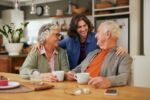 Happy smiling senior parents with adult daughter drinking tea
